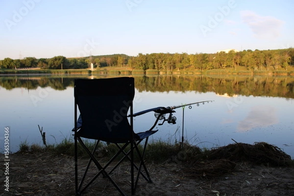 Obraz A tranquil fishing scene by a calm lake at sunset.