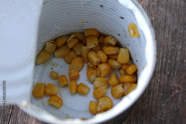 Obraz Open tin can with scattered yellow corn kernels inside.