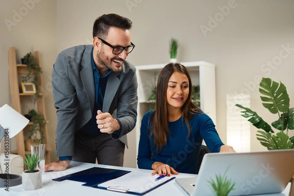 Obraz Businesspeople working together in office using laptop and smiling