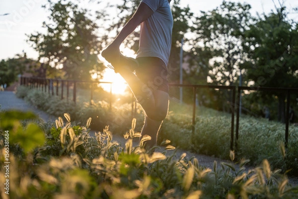 Fototapeta Man warming up before running in a park