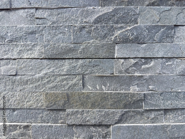 Fototapeta Close-up of textured gray stone wall with rough surface and stacked pattern