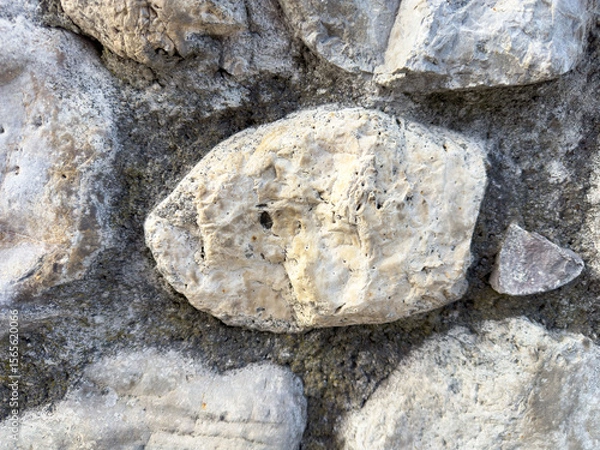 Fototapeta Close-up of natural stone wall texture with rough gray and beige rocks