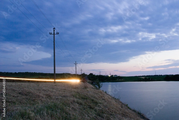Obraz A body of water with power lines on it and a sunset in the background
