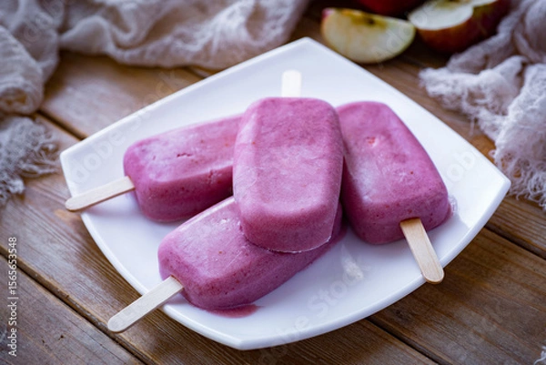 Fototapeta Berry ice cream on a stick on a white plate on a wooden table. Strawberry ice cream for dessert. Close-up