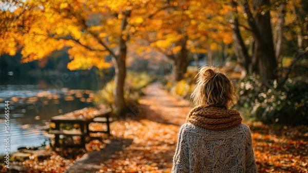 Fototapeta A woman explores an autumn park, enjoying the colorful foliage and peaceful scenery.