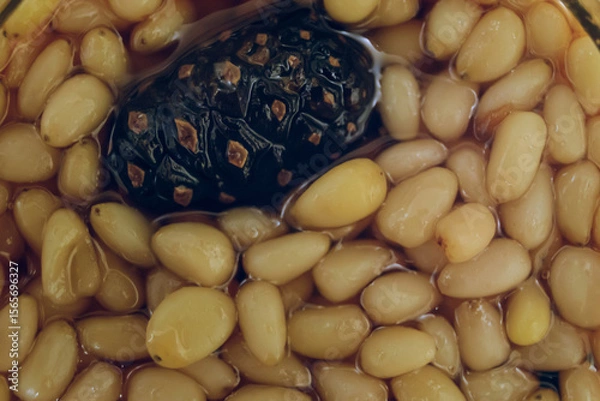 Fototapeta Pine nuts with young cones in in pine syrup. Siberian sweet treat.