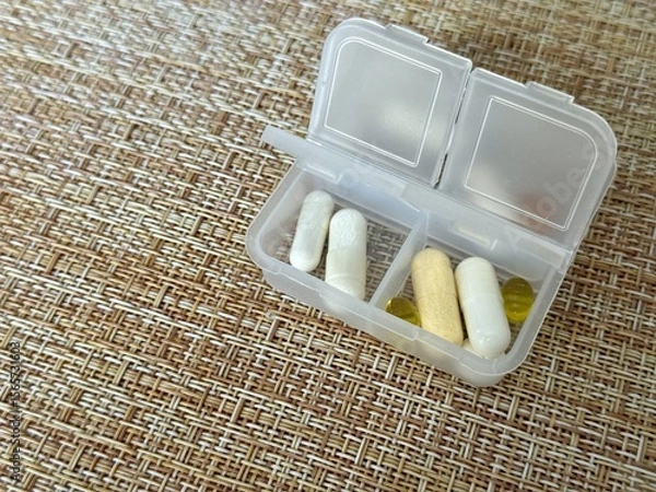 Obraz The weekly transparent pillbox is designed for convenient and efficient daily storage of dietary supplements and tablets. It has compartments with various types of capsules for administration.