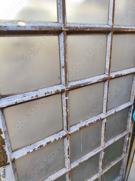 Fototapeta Rusty Vintage Industrial Window with Frosted Glass Panels and Weathered Metal Grid Frame Close-Up