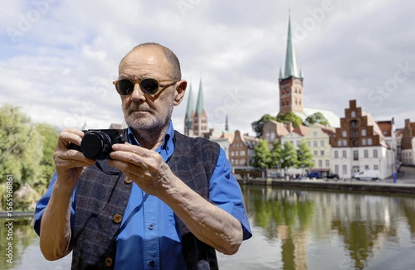 Fototapeta Man Photographing Historic Architecture Near a Scenic River on a Sunny Day