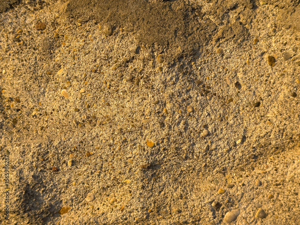 Fototapeta Close-up of rough sandy beach texture with small pebbles