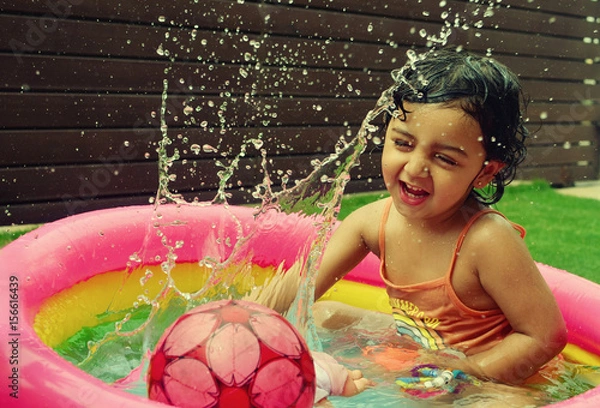 Obraz A girl enjoying in a water pool on a hot summer day!