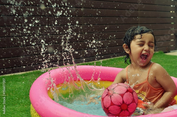 Obraz A girl enjoying in a water pool on a hot summer day!