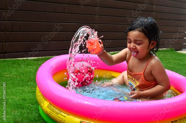 Obraz A girl enjoying in a water pool on a hot summer day!