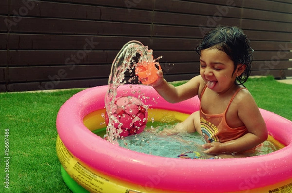 Obraz A girl enjoying in a water pool on a hot summer day!