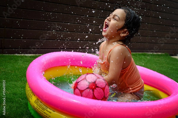 Obraz A girl enjoying in a water pool on a hot summer day!