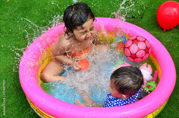 Obraz Sisters playing and enjoying in a small swimming pool