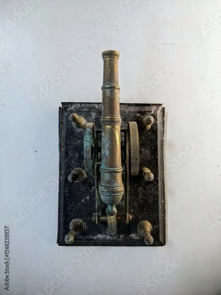 Fototapeta Antique brass artillery cannon still life on a distressed white table with grunge texture background. Top View.