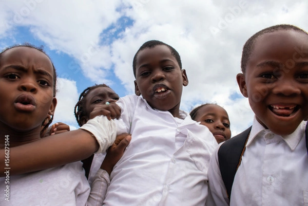 Fototapeta Happy African children in school uniforms enjoying time together outdoors. A genuine moment that reflects joy, education, and the powerful connection between learning. 