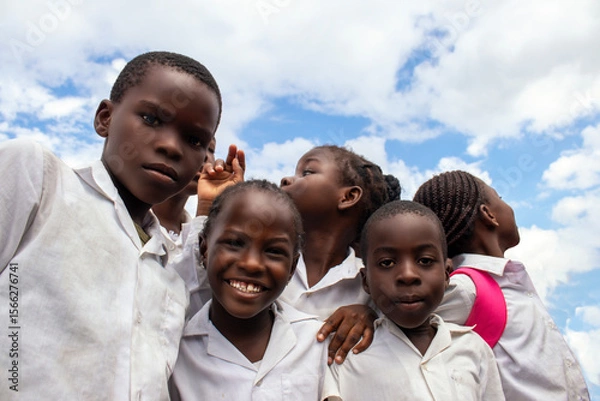 Fototapeta Happy African children in school uniforms enjoying time together outdoors. A genuine moment that reflects joy, education, and the powerful connection between learning. 