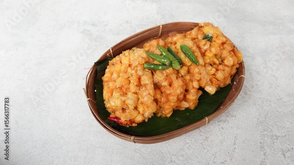 Obraz Perkedel Jagung or Bakwan Jagung, corn fritters is Indonesian traditional food. Savory snack made of corn, egg, flour, spring onion, pepper and salt. Served in wicker bamboo plate on grey background