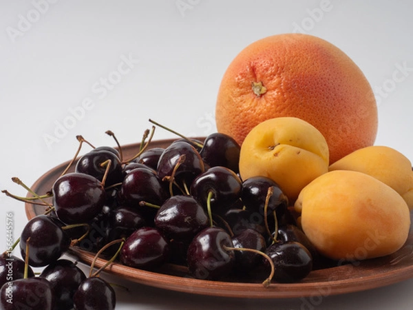 Fototapeta Sweet cherries with apricots isolated on white background cutout. Ripe berries closeup. Mix berries and fruits.
