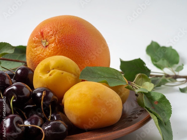 Fototapeta Sweet cherries with apricots isolated on white background cutout. Ripe berries closeup. Mix berries and fruits.