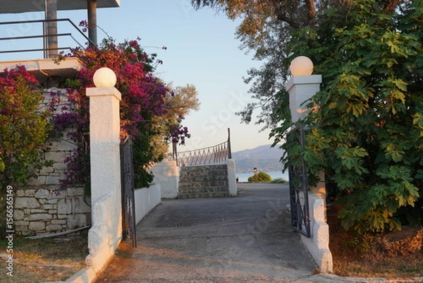 Obraz Sunset gateway in a serene coastal retreat framed by vibrant bougainvillea and lush greenery, inviting exploration in a tranquil seaside setting