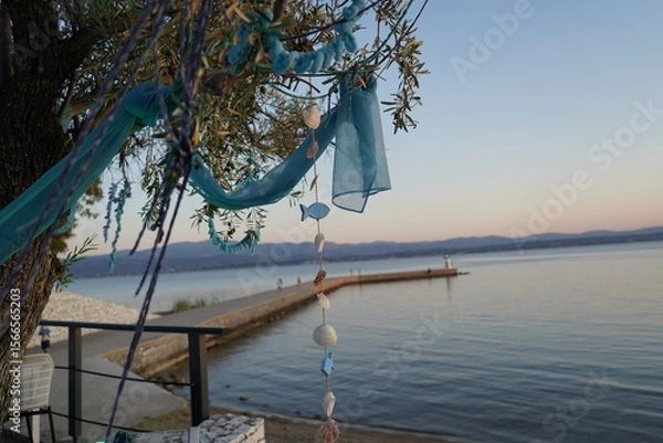 Obraz Waves gently shimmer at sunset near a tranquil lake adorned with handmade decorations, creating a serene escape for wanderers and nature lovers alike