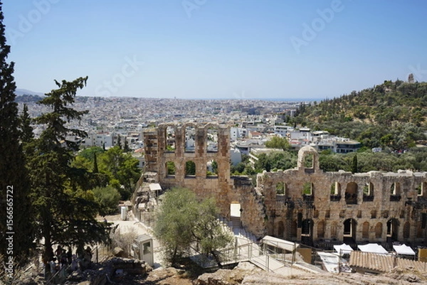 Obraz Ancient ruins of Herodes Atticus theater overlook a bustling Athens, sunlit hills and vibrant city life blend in perfect harmony at midday