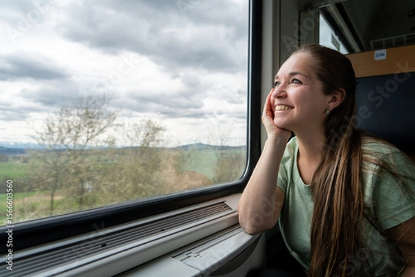 Obraz Mujer feliz y sonriente mirando por la ventana durante su viaje en tren