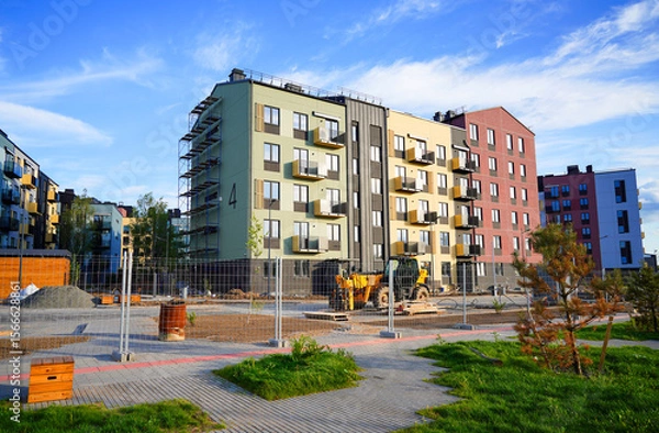 Obraz Building construction. Modern Residential condo. Residential Building renovation. Modern condominium with multi-colored facade on construction site. Scaffolding for painting residential building.