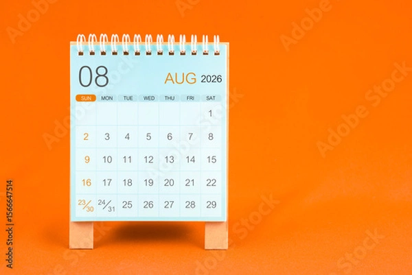 Fototapeta August 2026 desk calendar stand on orange color textile background.