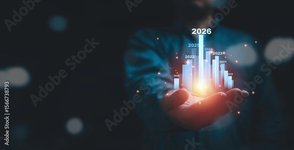 Fototapeta Businessman holding glowing virtual technical graph and chart for analysis stock market in 2026, technology investment and value investment concept.