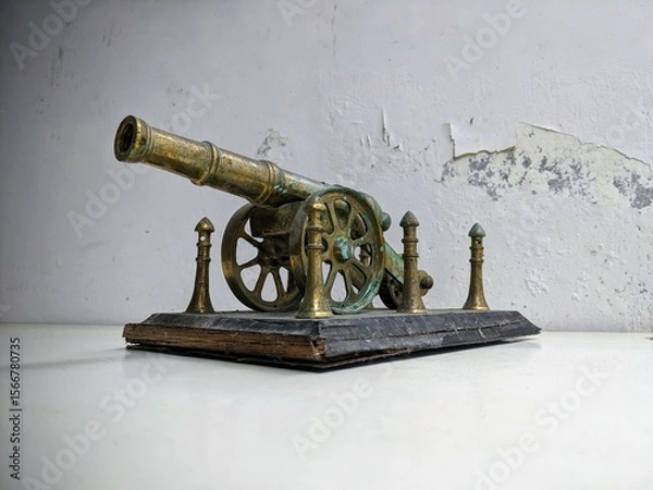 Fototapeta Antique brass artillery cannon still life on a distressed white table with grunge texture background. Three Quarter View