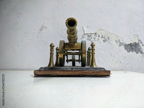 Fototapeta Antique brass artillery cannon still life on a distressed white table with grunge texture background. Front View
