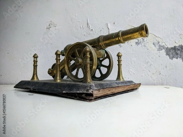 Fototapeta Antique brass artillery cannon still life on a distressed white table with grunge texture background. Three Quarter View