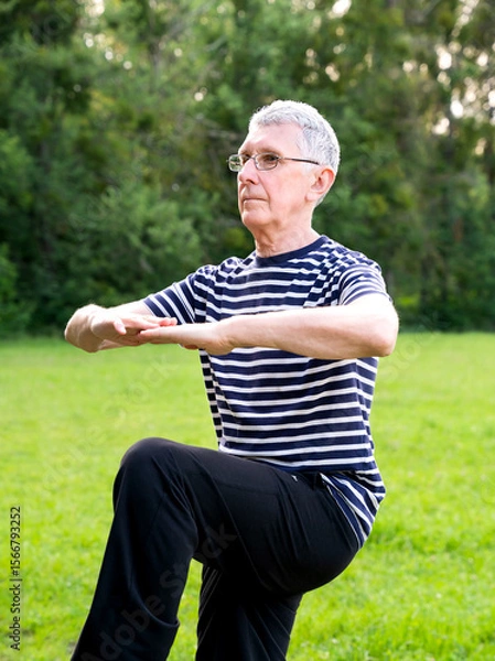 Fototapeta Mature retired wearing glasses plays sports in a city park during routine workout in morning. Staying active after retirement.