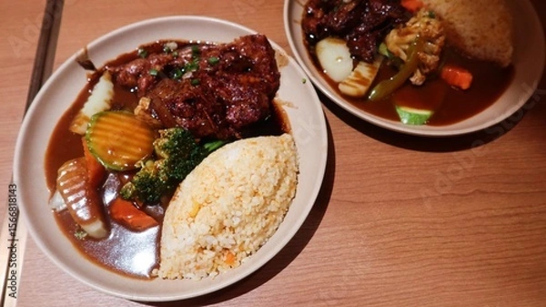 Fototapeta close up of Japanese Pork Cartilage curry with rice, served with vegetables, including broccoli, carrots, and zucchini on a wooden table
