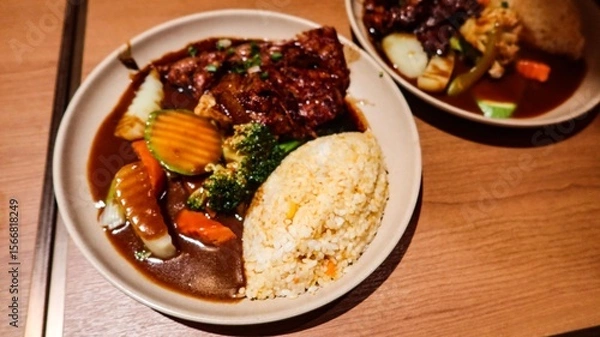 Fototapeta close up of Japanese Pork Cartilage curry with rice, served with vegetables, including broccoli, carrots, and zucchini on a wooden table