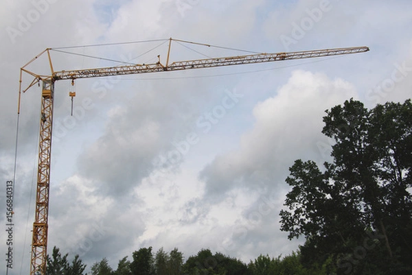 Obraz Yellow construction crane against cloudy sky