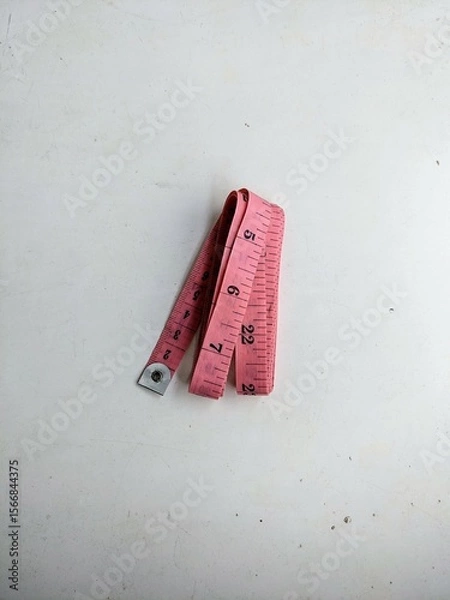 Fototapeta Pink tailor's measuring tape folded and isolated on a white background. Sewing, craft, and body measurement concept.