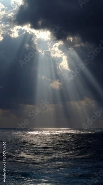 Obraz Sunlight beams through storm clouds over the ocean creating atmospheric scene