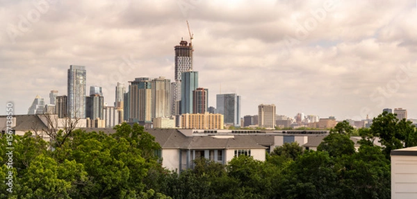 Fototapeta Austin skyline with trees, buildings, and construction crane.