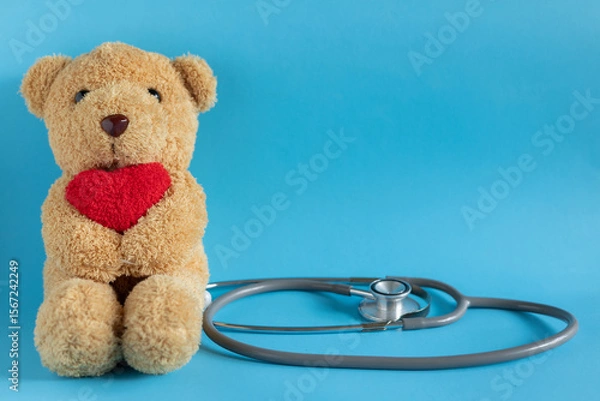 Fototapeta close up teddy bear with heart as paediatrician with stethoscope and heart on blue color background for representative of medical as kid and childhood concept