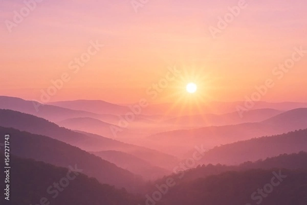 Fototapeta A tranquil sunrise paints soft pastel hues across rolling mist-covered mountains, creating a serene and dreamlike atmosphere.
