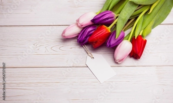 Obraz Multicolor tulip bouquet is lying on painted wooden plank in flat design with blank gift tag