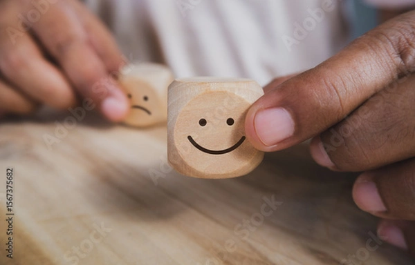 Obraz Hand holding wood cube with smile icon, World mental health day or feedback rating concept, Positive customer review, Wood cube stacking with emotion face icon on wood background