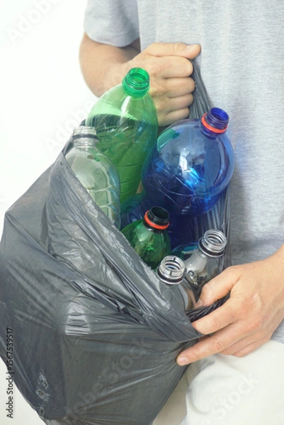Fototapeta Plastic bottles different colors and sizes in black garbage bag held by man, close-up photo. Concepts of household recycling, waste separation, eco-conscious lifestyle and plastic pollution solution.