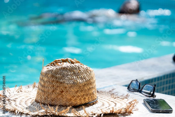 Fototapeta Close up of a straw hat and other objects of a local Costa Rican man taking a dip in the pool in Tortuguero, Costa Rica