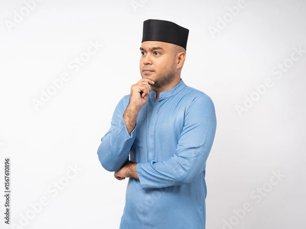 Obraz Portrait happy young asian muslim man thinking on isolated white background. Islamic Attractive Muslim man wearing songkok cap islam costume.